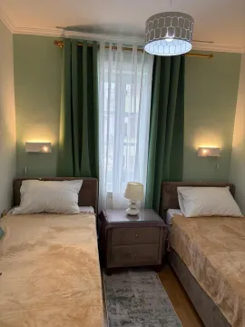 Uređena spavaća soba sa dva singl kreveta i noćnim stočićem. - image 7