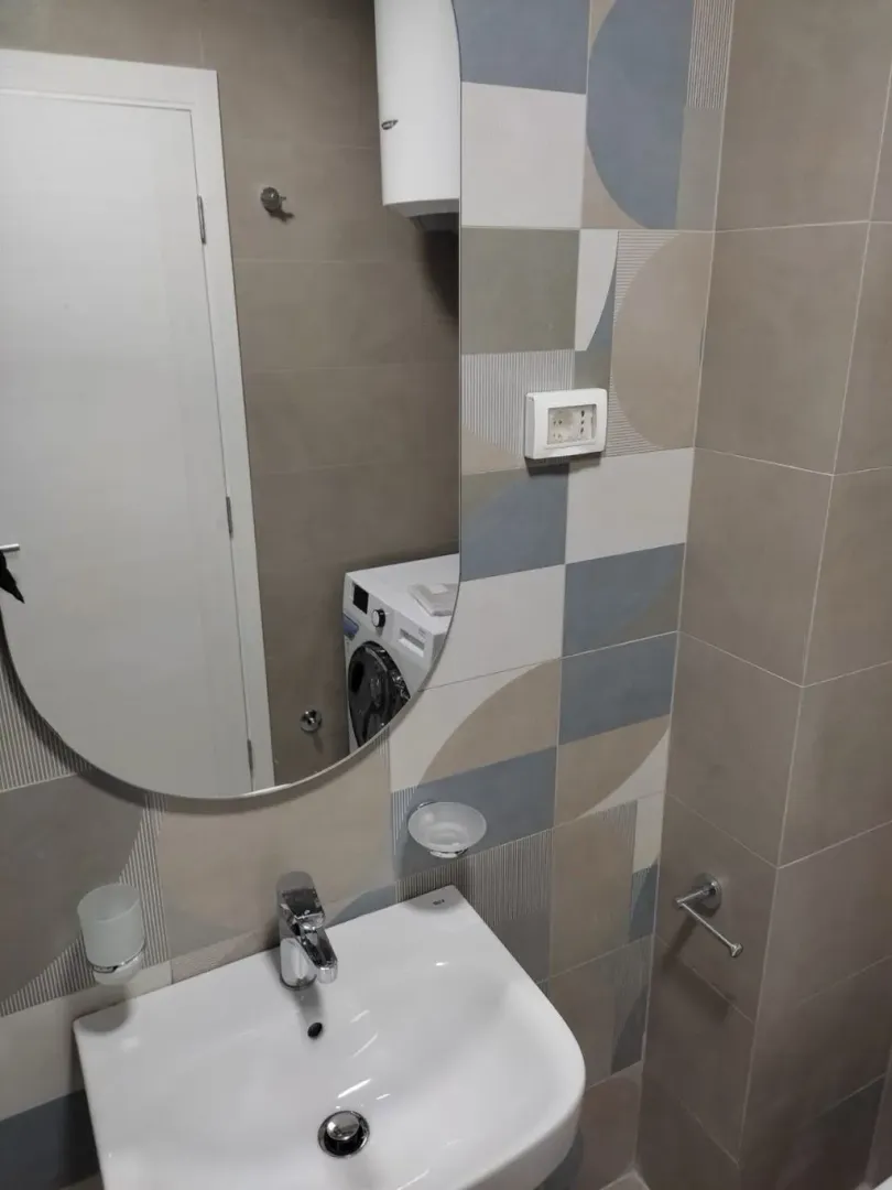 Bathroom with a sink, mirror, and modern style tiles.