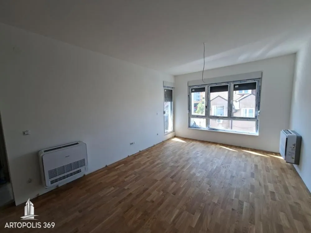 Prazna neuređena soba sa parketom na podu i prozorima.