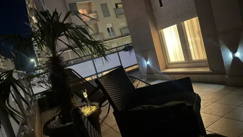 Osvijetljena terasa sa garniturom za sjedenje i pogledom noću. - image 17