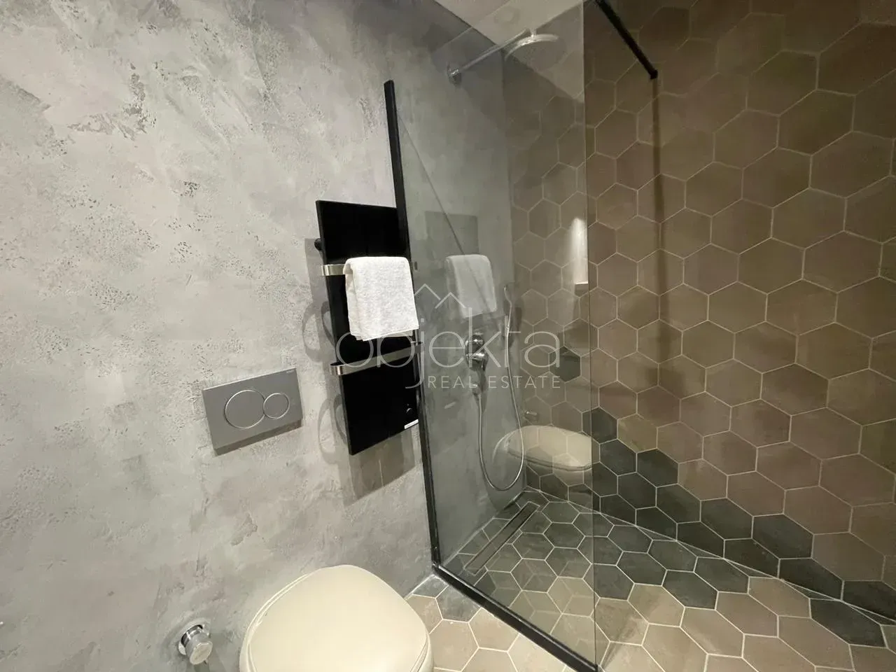 Modernly equipped bathroom with a walk-in shower and decorative tiles.