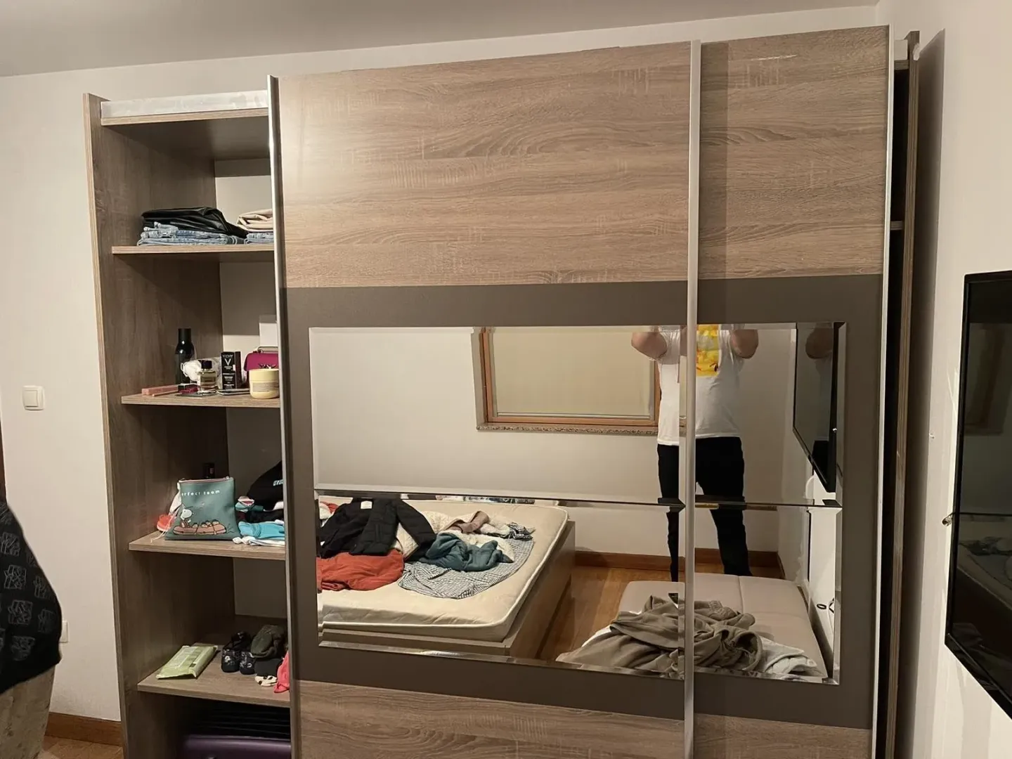 Spavaća soba sa velikim drvenim garderoberom koji ima ogledalo.