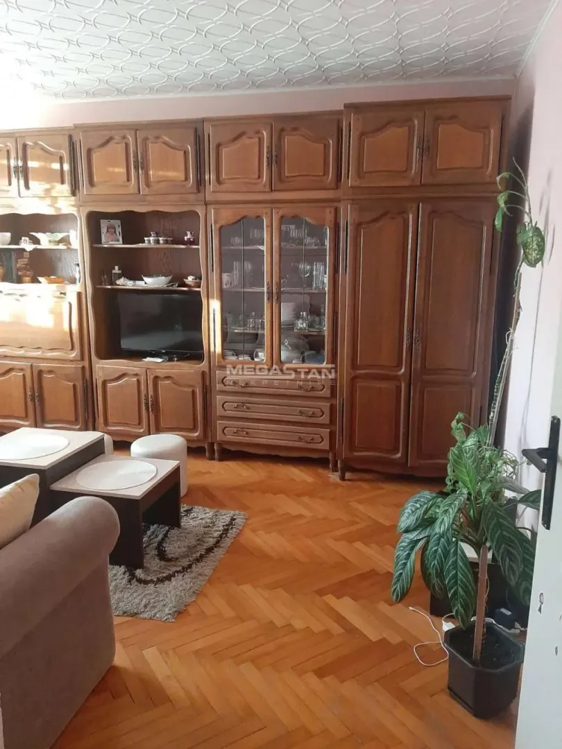 Dnevna soba sa drvenim nameštajem i parketom na podu.