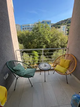 Namješten balkon sa dvije fotelje i stočićem, sa pogledom na zelenilo i okolne zgrade. - image 2