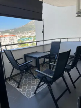 Namještena terasa sa garniturom za sedenje i pogledom na grad i planine. - image 4