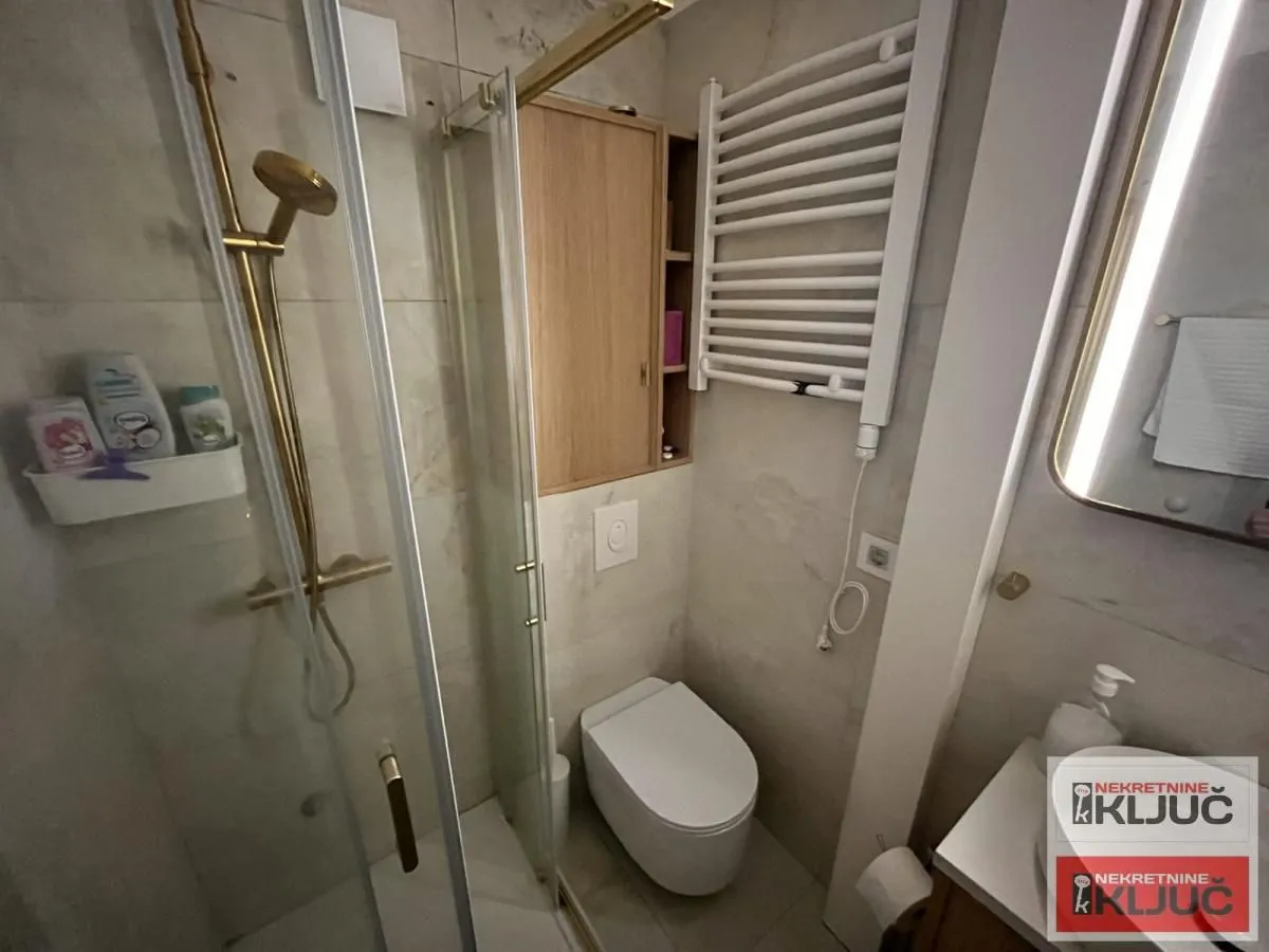 Moderno opremljeno kupatilo sa tuš kabinom, WC šoljom i umivaonikom.