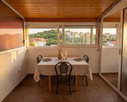 Enclosed terrace with a dining table and a view of the neighborhood and nature. - image 8