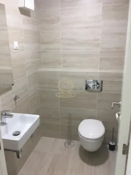 Smaller bathroom tiled in beige tones with a washbasin and toilet. - image 5