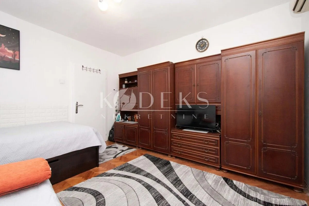 Furnished bedroom with large wooden wardrobes, bed, and television.