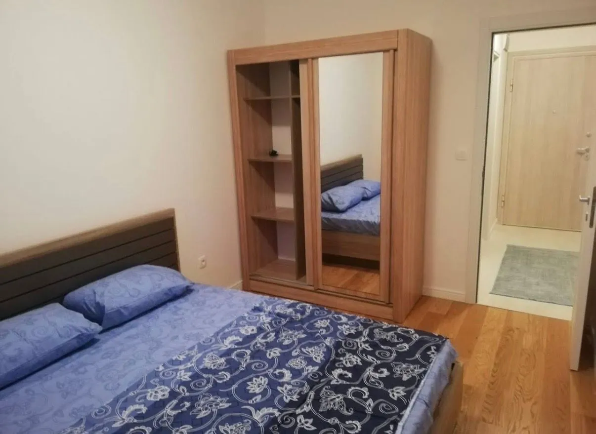 Furnished bedroom with a double bed and a wooden wardrobe.
