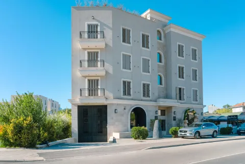 Exterior of a modern multi-family building with balconies and ground-level parking. - image 4