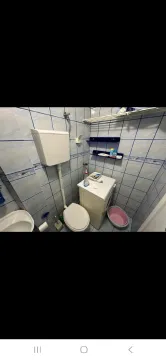 Manje kupatilo sa pločicama u plavim tonovima, wc šoljom i veš mašinom. - image 9