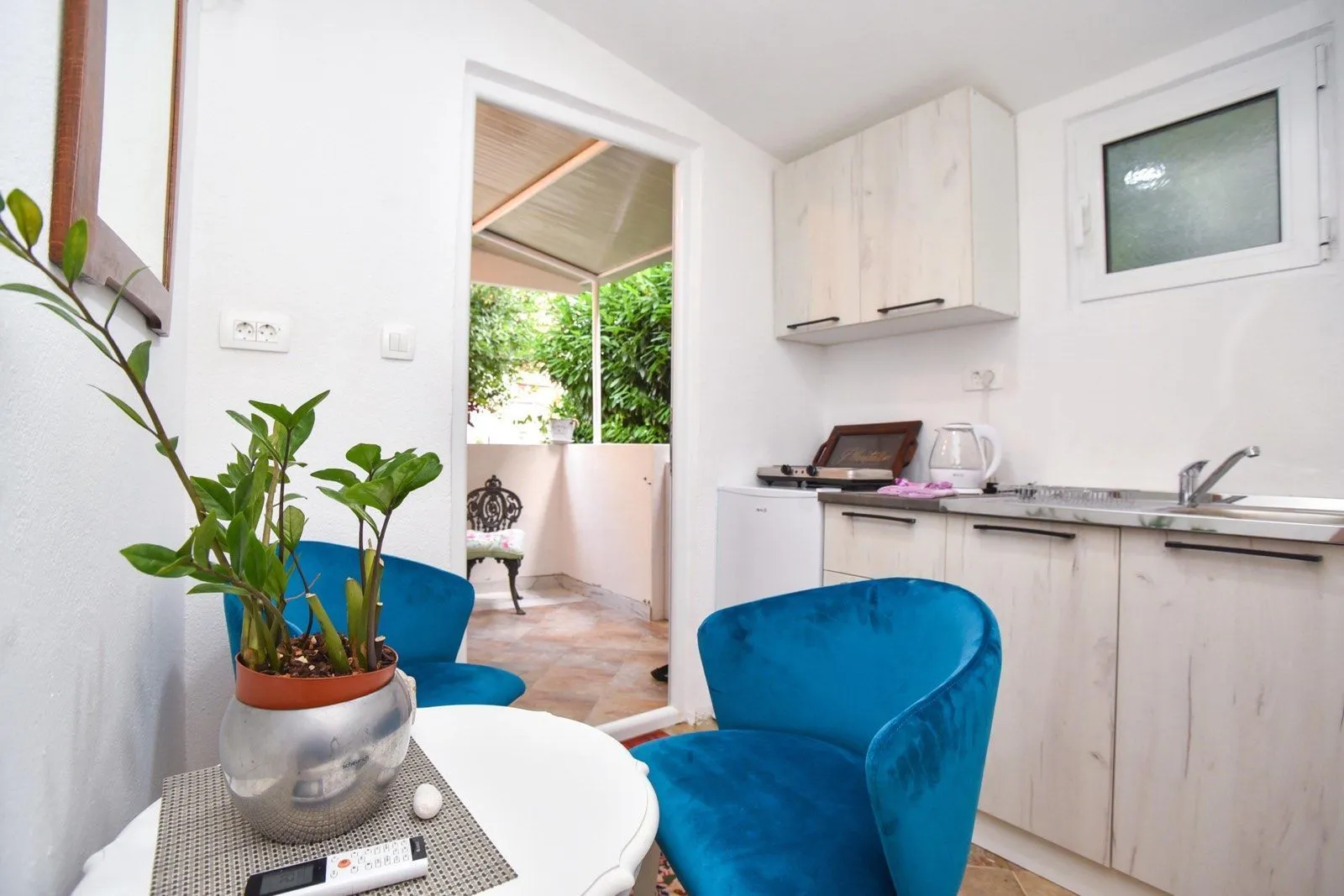 Small kitchen with a dining table and blue armchairs, with access to the terrace.