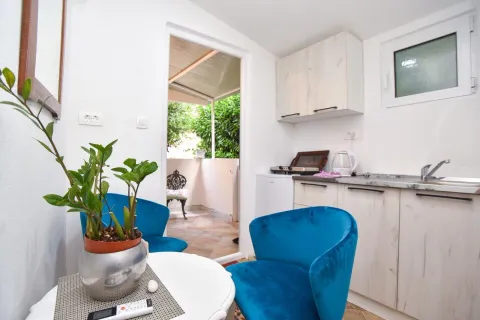Small kitchen with a dining table and blue armchairs, with access to the terrace. - image 9
