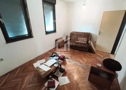 Living room with wooden parquet flooring, sofa, and scattered items on the floor. - image 2