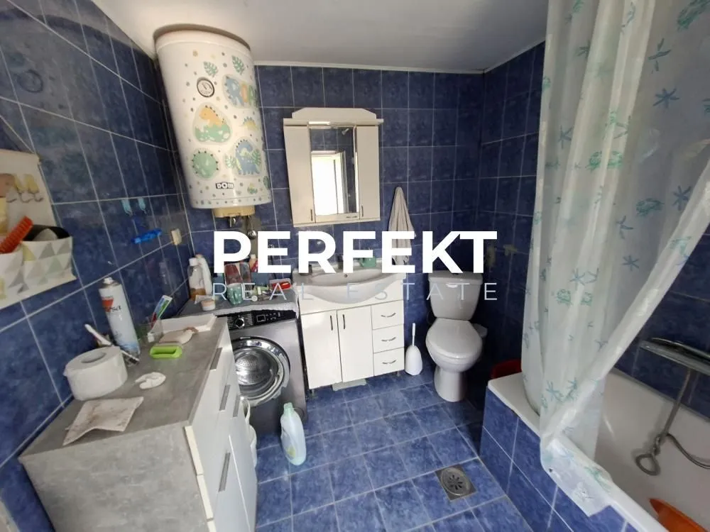 Kupatilo obloženo plavim pločicama sa kadom, toaletom i umivaonikom.