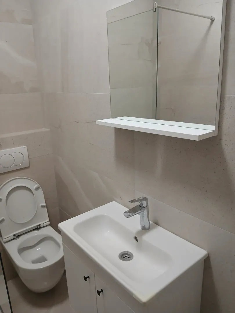 Bright bathroom with a sink, mirror, and toilet.