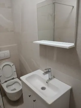 Bright bathroom with a sink, mirror, and toilet. - image 8