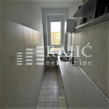 Small narrow kitchen with wall tiles and a sink. - image 4