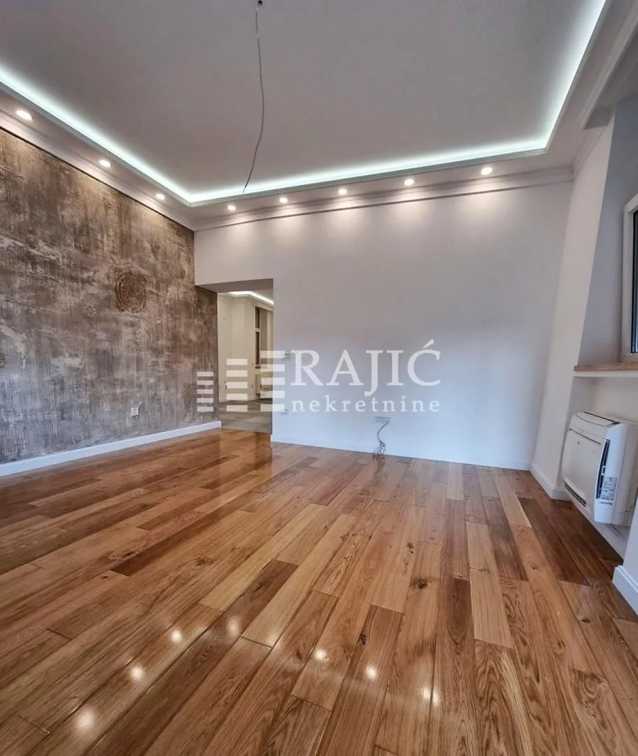 Empty living room with wooden flooring and a decorative wall.