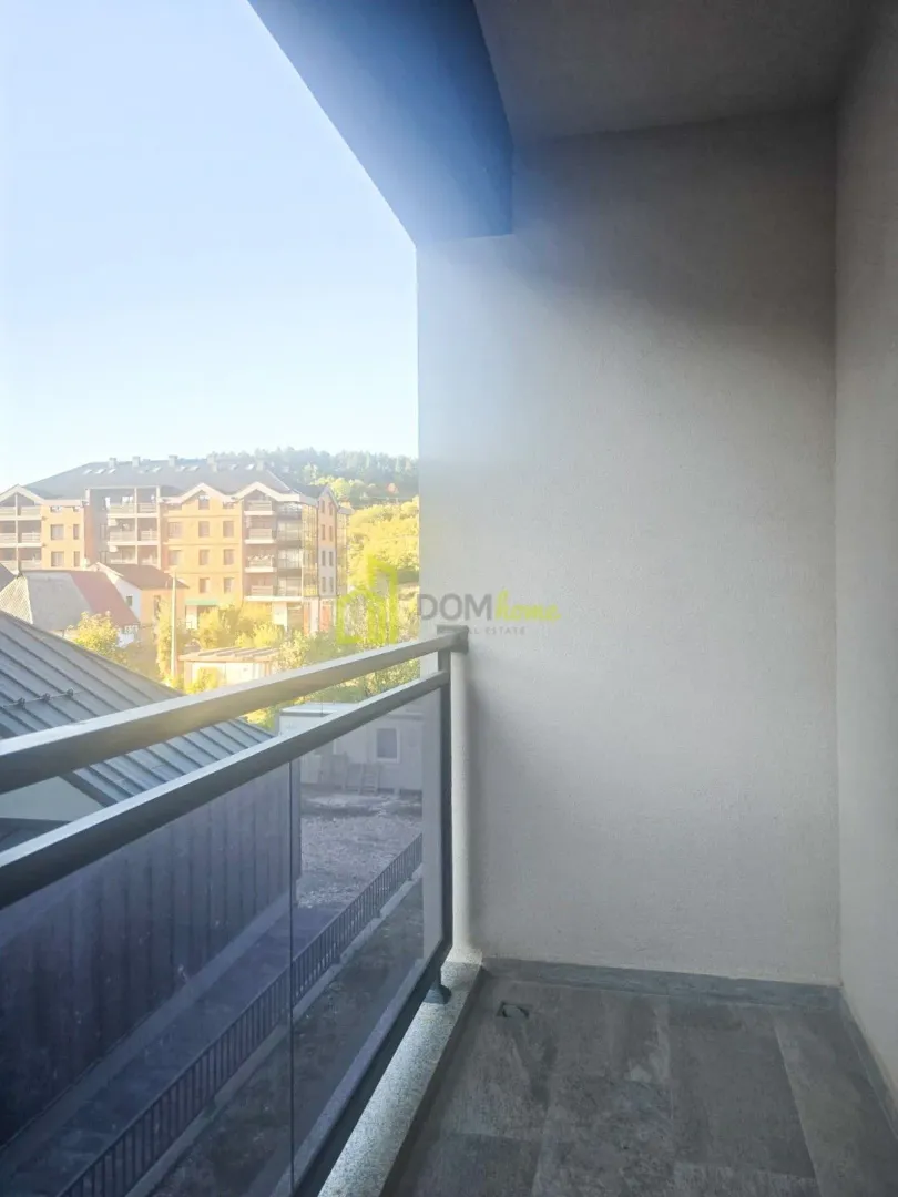Unfurnished covered balcony with a view of surrounding buildings and greenery.