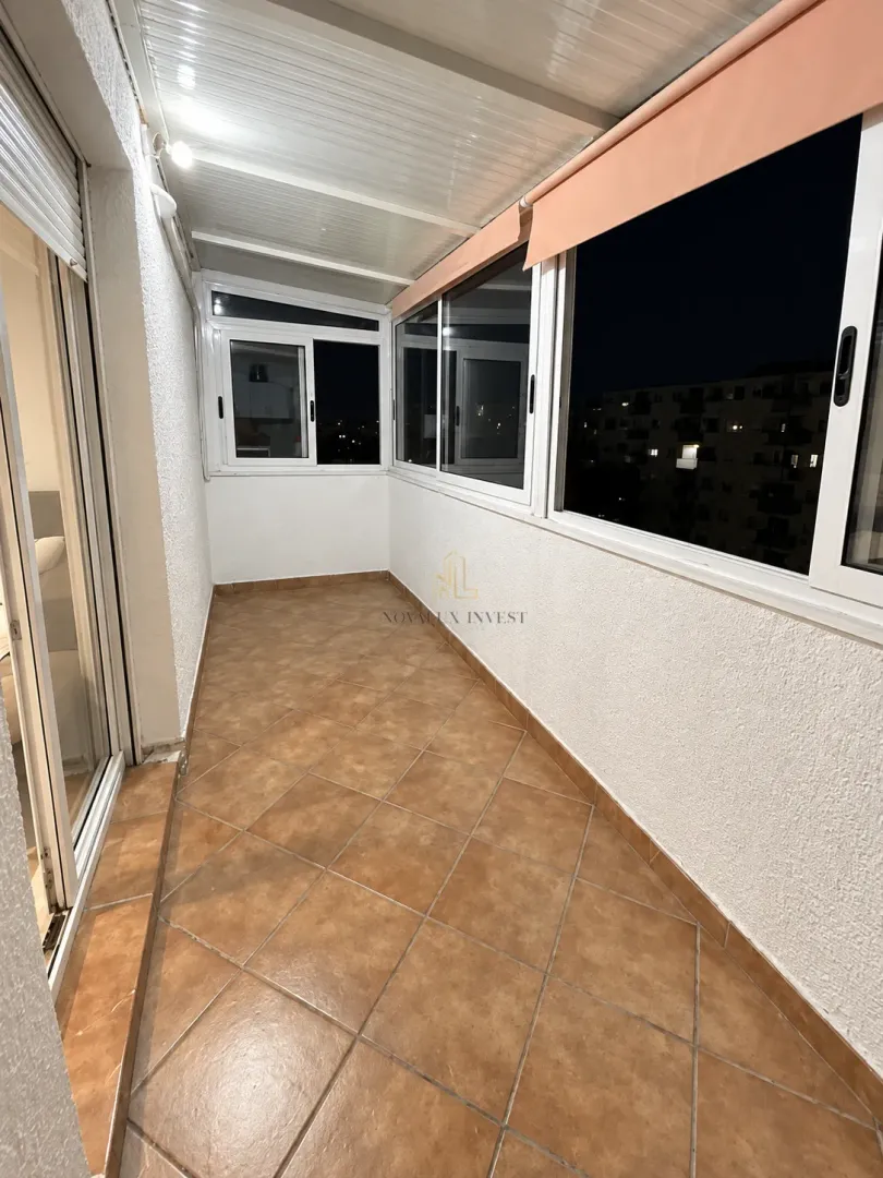 Zastakljeni balkon sa keramičkim pločicama na podu.