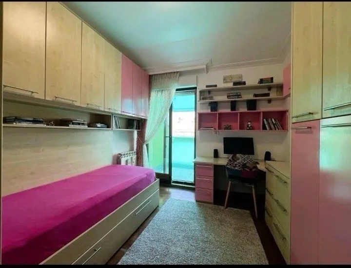Dječija soba sa krevetom, radnim stolom i ugradnim ormarima.