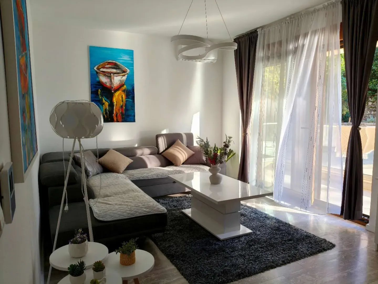 Bright living room with a sectional sofa, white coffee table, and large balcony doors.