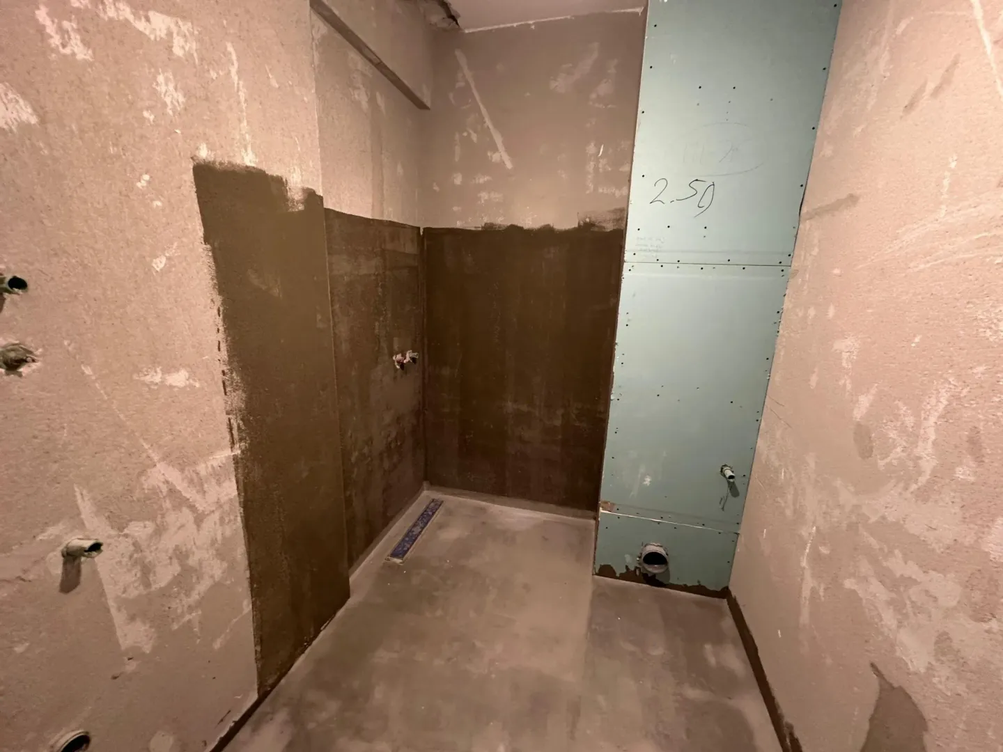 View of a room under construction with prepared plumbing installations.