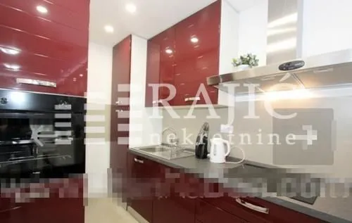 Modern kitchen with red cabinetry and built-in appliances.