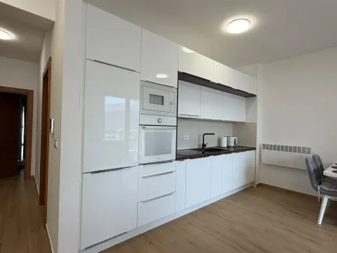 Moderna bijela kuhinja sa ugrađenim aparatima i trpezarijskim stolom. - image 6
