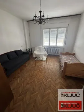 Dnevna soba sa garniturom za sedenje, krevetom i drvenim podom. - image 2