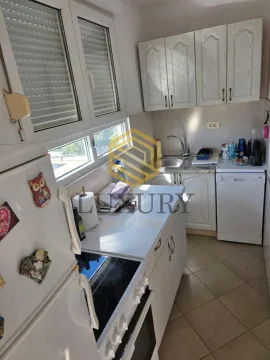 Small equipped kitchen with white cabinets and a window. - image 9
