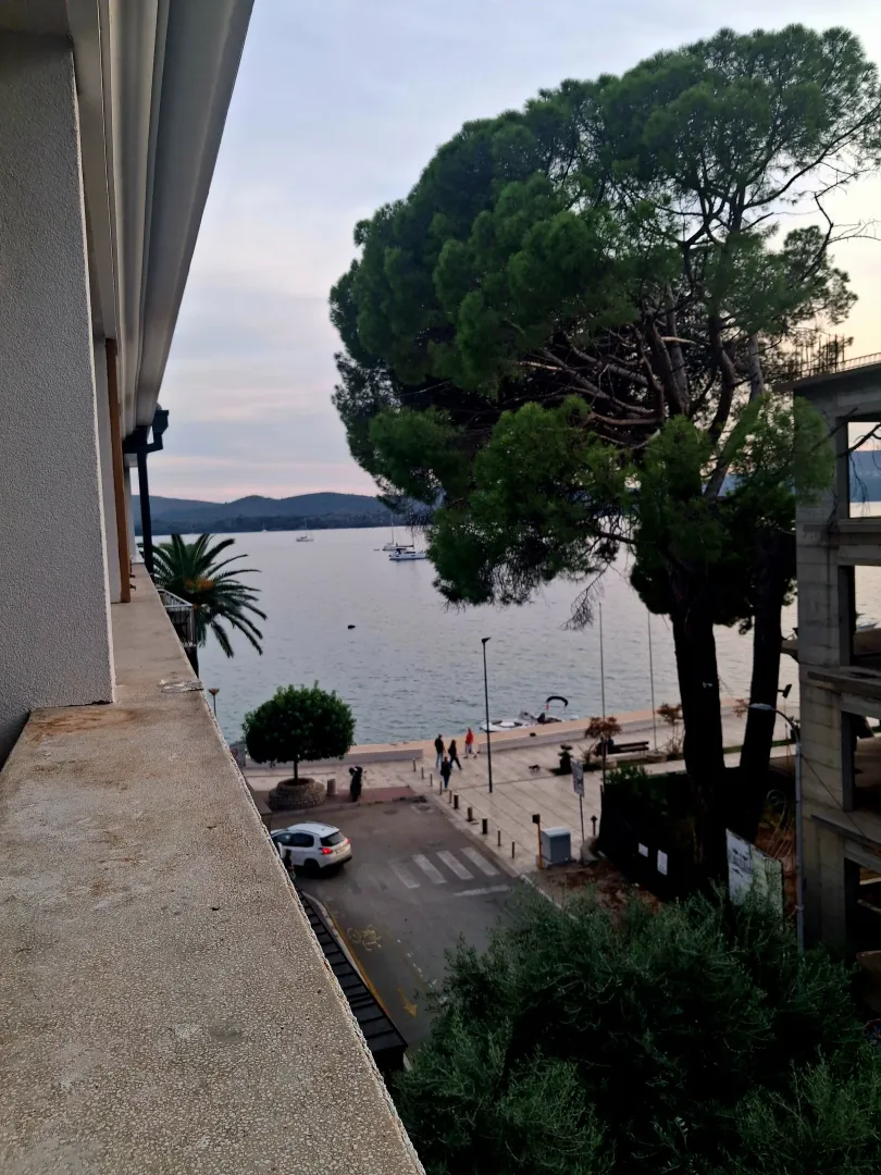 Pogled na more sa terase sa drvećem i šetalištem u okolini.