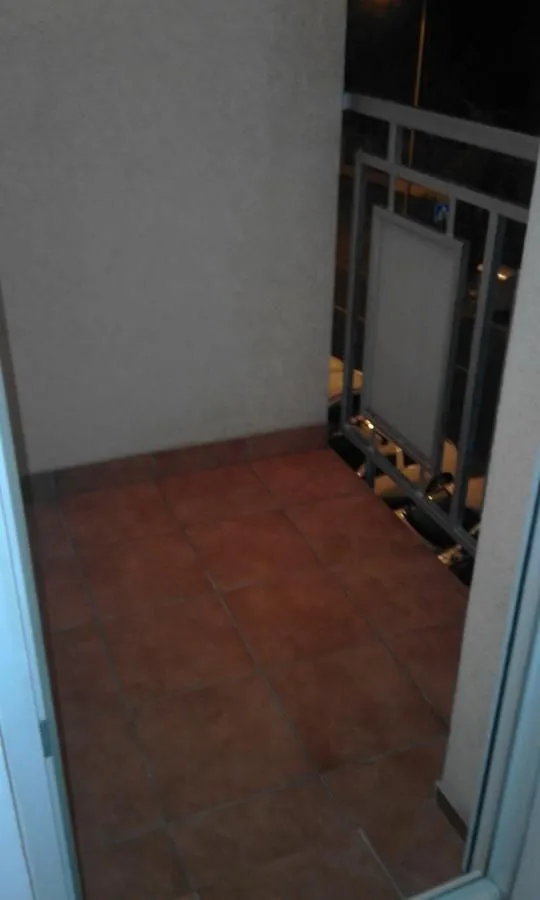 Manji popločani balkon sa metalnom ogradom.