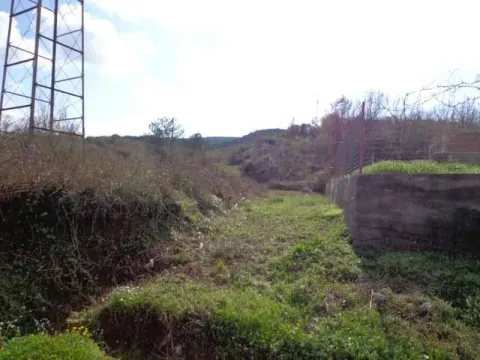 Pogled na neuređeni plac sa rastinjem i stubom dalekovoda u blizini. - image 3