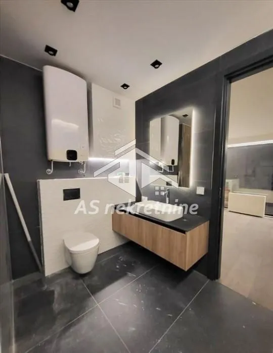 Modern bathroom with a walk-in shower, washbasin, and water heater.