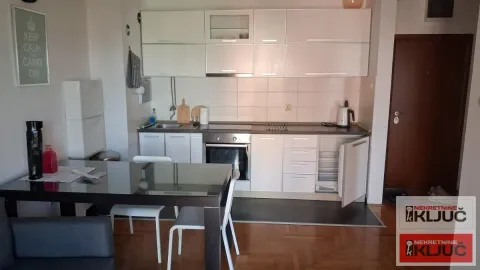 Kuhinja opremljena belim elementima i trpezarijski sto sa stolicama. - image 9