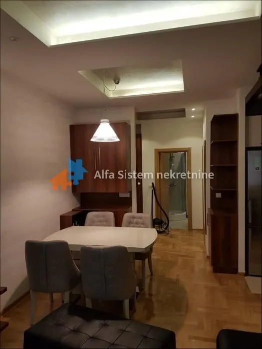 Trpezarija sa stolom i stolicama, povezana sa dnevnim boravkom.