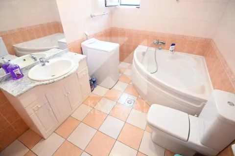 Bathroom equipped with a corner bathtub, vanity with sink, toilet, and washing machine. - image 22