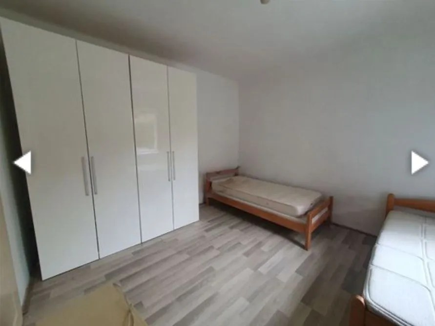 Bedroom with a large white wardrobe and wooden beds.