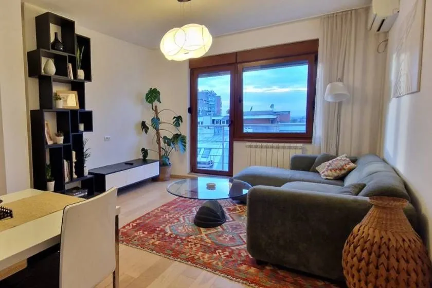 Living room with a sofa, shelving unit, and a large window.