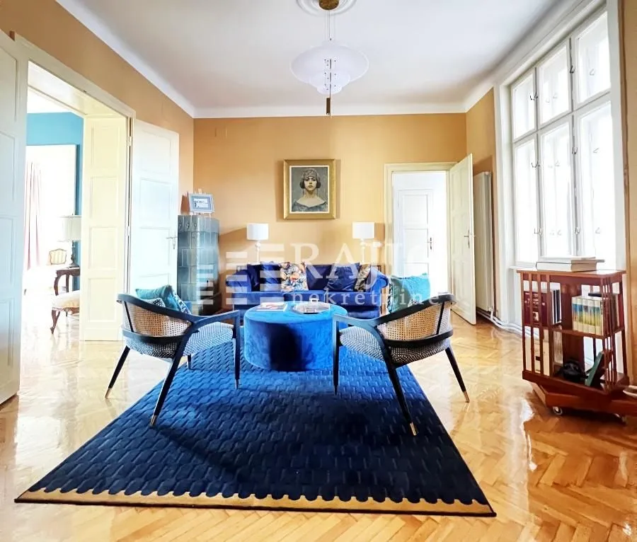Spacious and bright living room with seating area and parquet flooring.