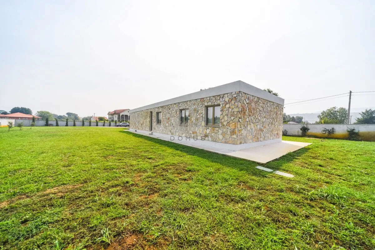 Single-story stone-clad house with a large grassy yard.