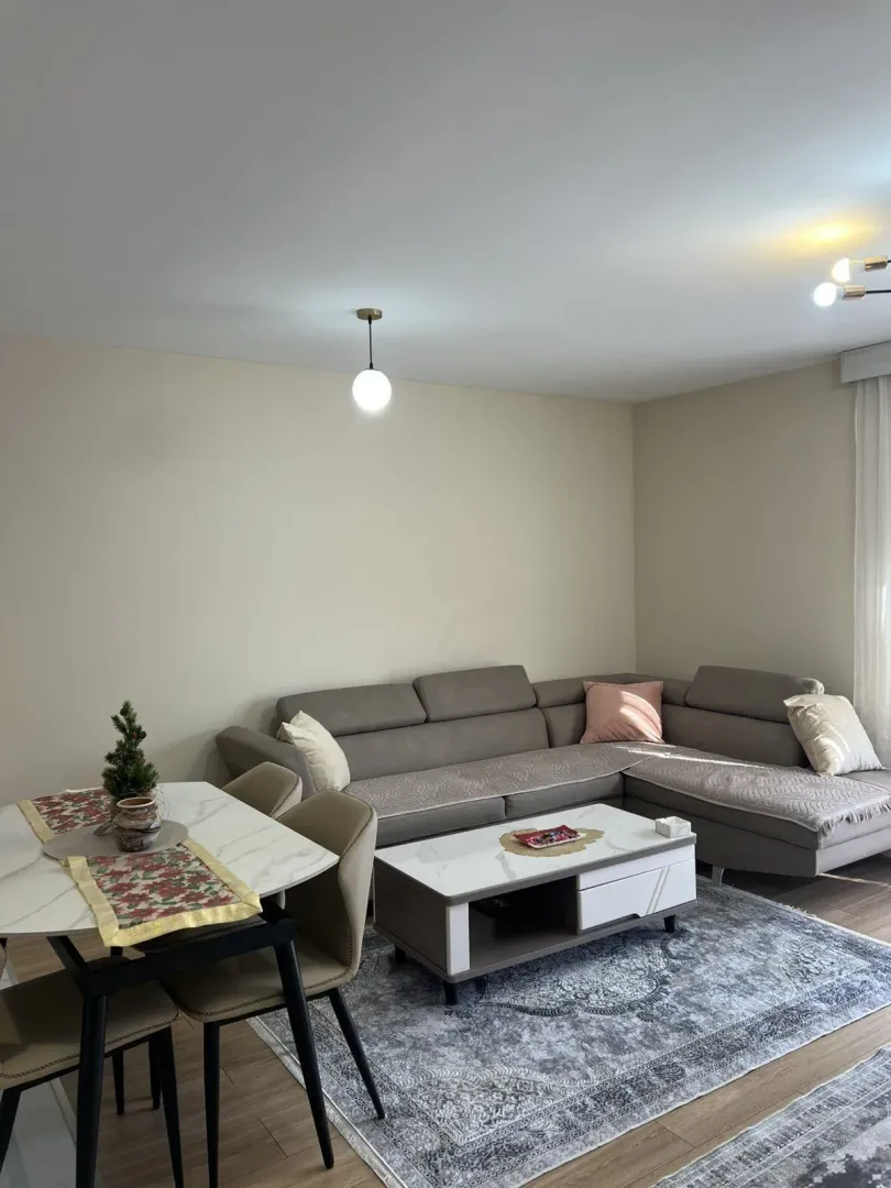Bright living room with a corner sofa and a dining table.