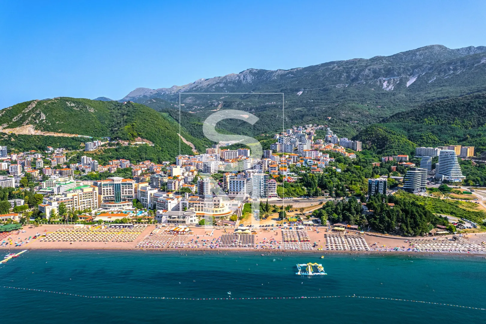 Aerial view of the sea coast, beach, and town at the foot of the mountain.
