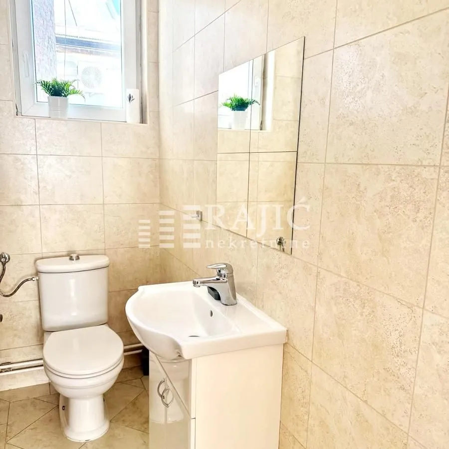 Smaller bathroom with light tiles, washbasin and toilet bowl.