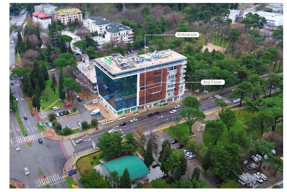 Aerial view of a modern commercial and residential building surrounded by trees.