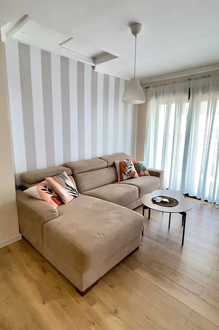 Living room with a corner sofa, coffee table, and striped wallpaper.