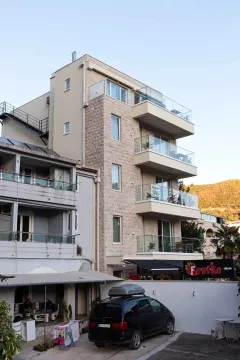 Pogled na spoljašnjost višespratne stambene zgrade sa terasama i kamenom fasadom. - image 40